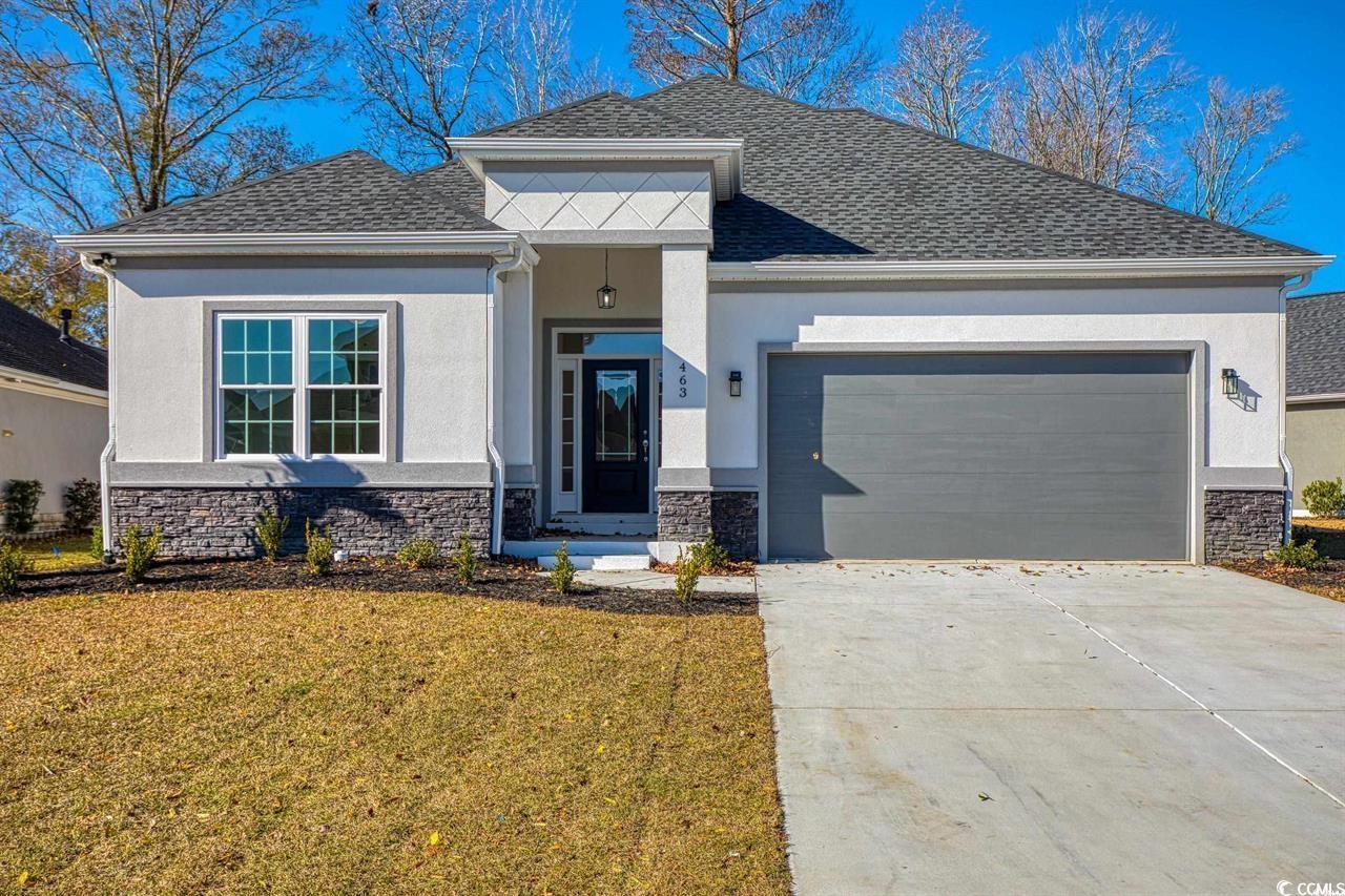 View of front facade with stone siding, an attached garage, and driveway