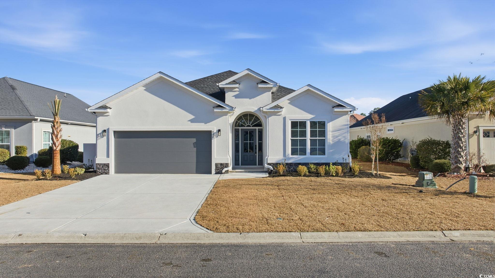 View of front facade with driveway, stucco siding, a garage, and stone siding