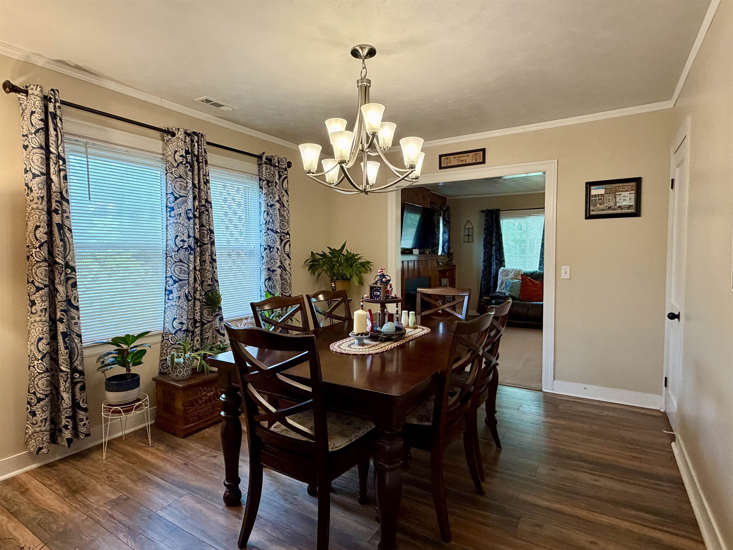 206 Burns Road Ramer, TN 38367 - Photo 7 of 37 Dining area featuring wood-finish flooring, a contemporary chandelier, two windows with blinds, and painted crown molding