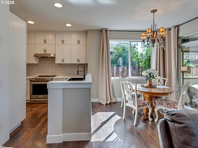 a kitchen with stainless steel appliances granite countertop a stove a refrigerator a kitchen island a table and chairs in it