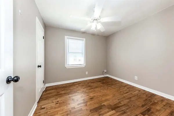 an empty room with a chandelier fan and windows
