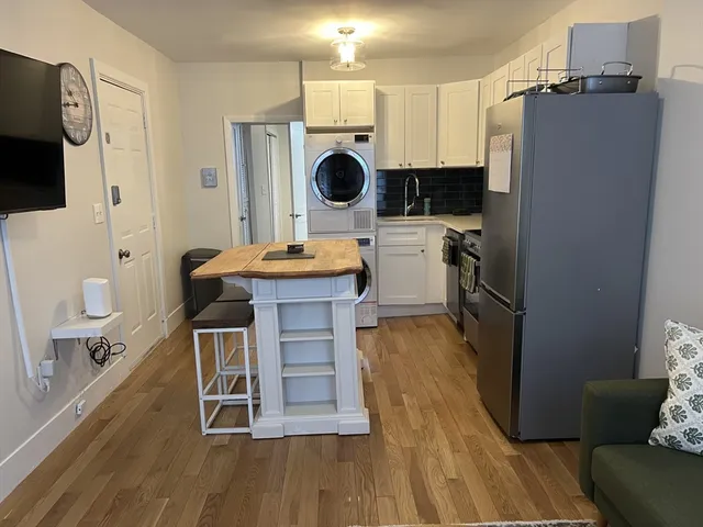 a kitchen with stainless steel appliances a stove a microwave a refrigerator a dining table and chairs with wooden floor