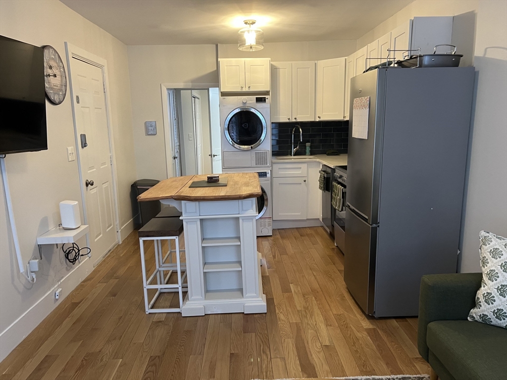 35 Grove Street, Unit 3 Boston, MA 02114 - Photo 6 of 20 a kitchen with stainless steel appliances a stove a microwave a refrigerator a dining table and chairs with wooden floor
