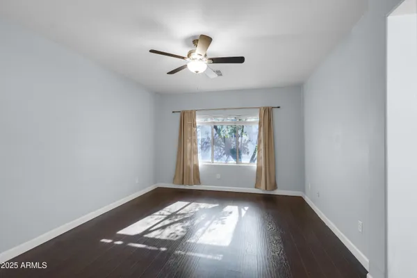 a view of empty room with wooden floor and fan