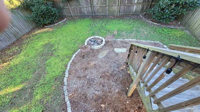 a view of a backyard with plants and wooden fence