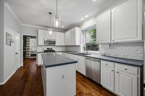a kitchen with kitchen island granite countertop a sink window and cabinets