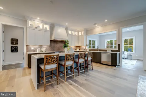 a kitchen with stainless steel appliances granite countertop a table chairs sink and cabinets