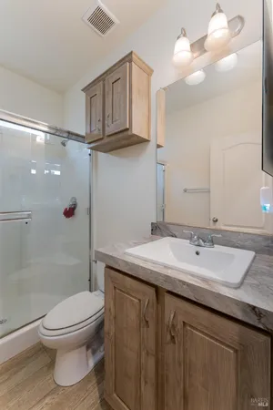 a bathroom with a granite countertop sink a toilet and shower