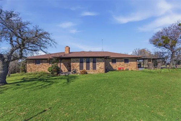 a view of a big house with a big yard and large trees
