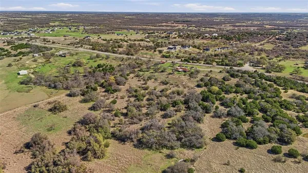 an aerial view of residential houses with outdoor space and trees