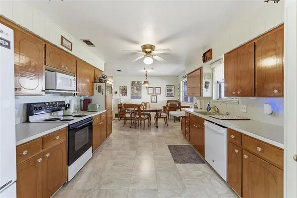 an open kitchen with stainless steel appliances granite countertop a stove top oven a sink dishwasher a dining table and chairs with wooden cabinets