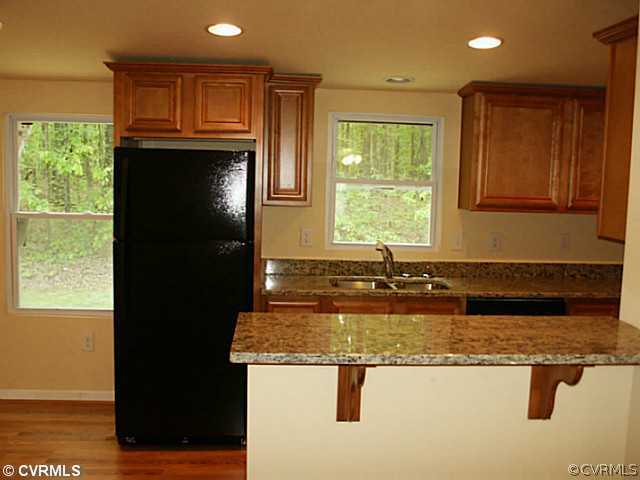 168 Dusty Road Bumpass, VA 23024 - Photo 3 of 6 a kitchen with granite countertop a refrigerator a stove a sink and a cabinets