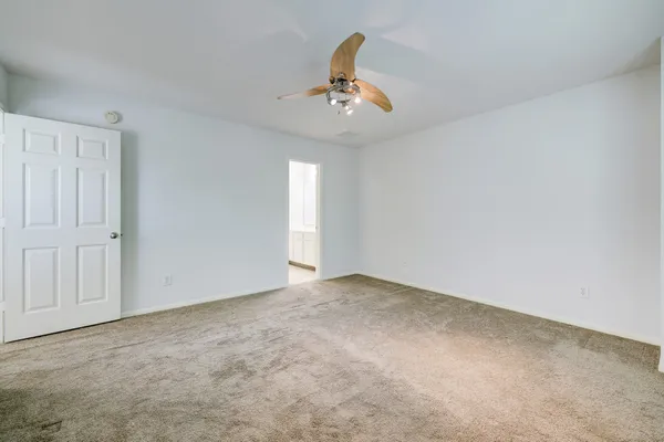 an empty room with windows and ceiling fan