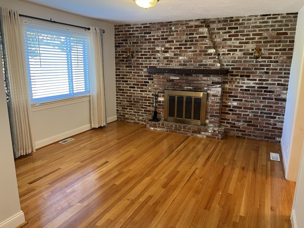 21 Grove Street Saugus, MA 01906 - Photo 3 of 10 a view of empty room with wooden floor and fireplace