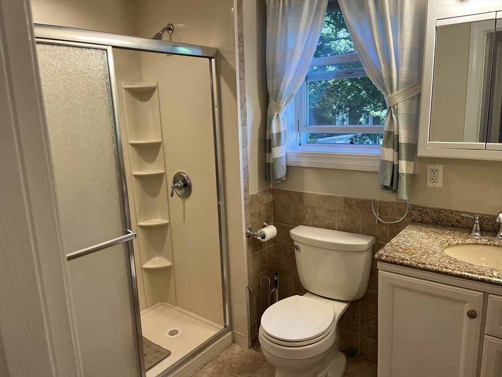 21 Grove Street Saugus, MA 01906 - Photo 5 of 10 a bathroom with a granite countertop toilet a sink and a shower