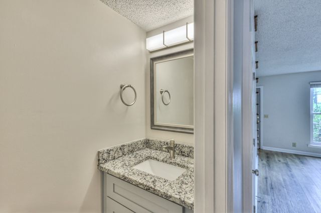 a bathroom with a granite countertop sink a mirror and shower