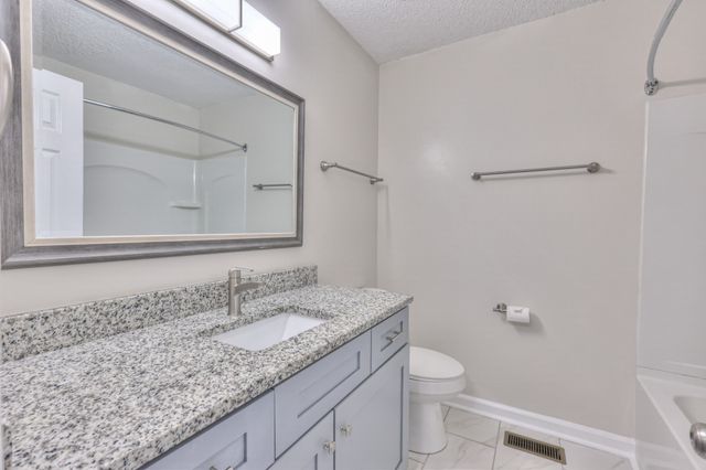 a bathroom with a granite countertop sink a toilet and a mirror