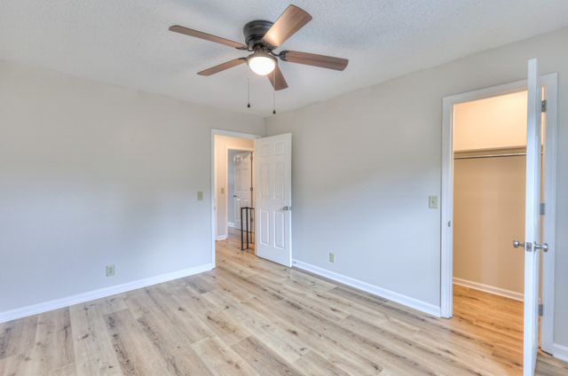 an empty room with wooden floor fan and windows