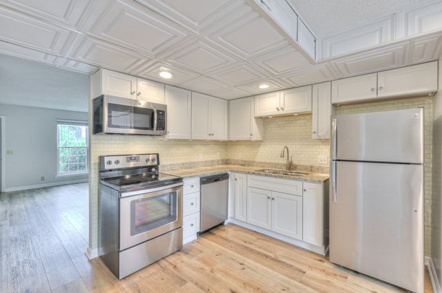 a kitchen with stainless steel appliances granite countertop a refrigerator a stove top oven a sink and dishwasher with wooden floor