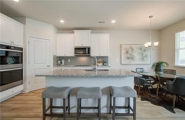 a kitchen with stainless steel appliances granite countertop a table chairs microwave and sink