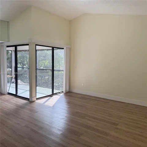 a view of an empty room with wooden floor and a large window
