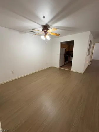 an empty room with chandelier fan and windows