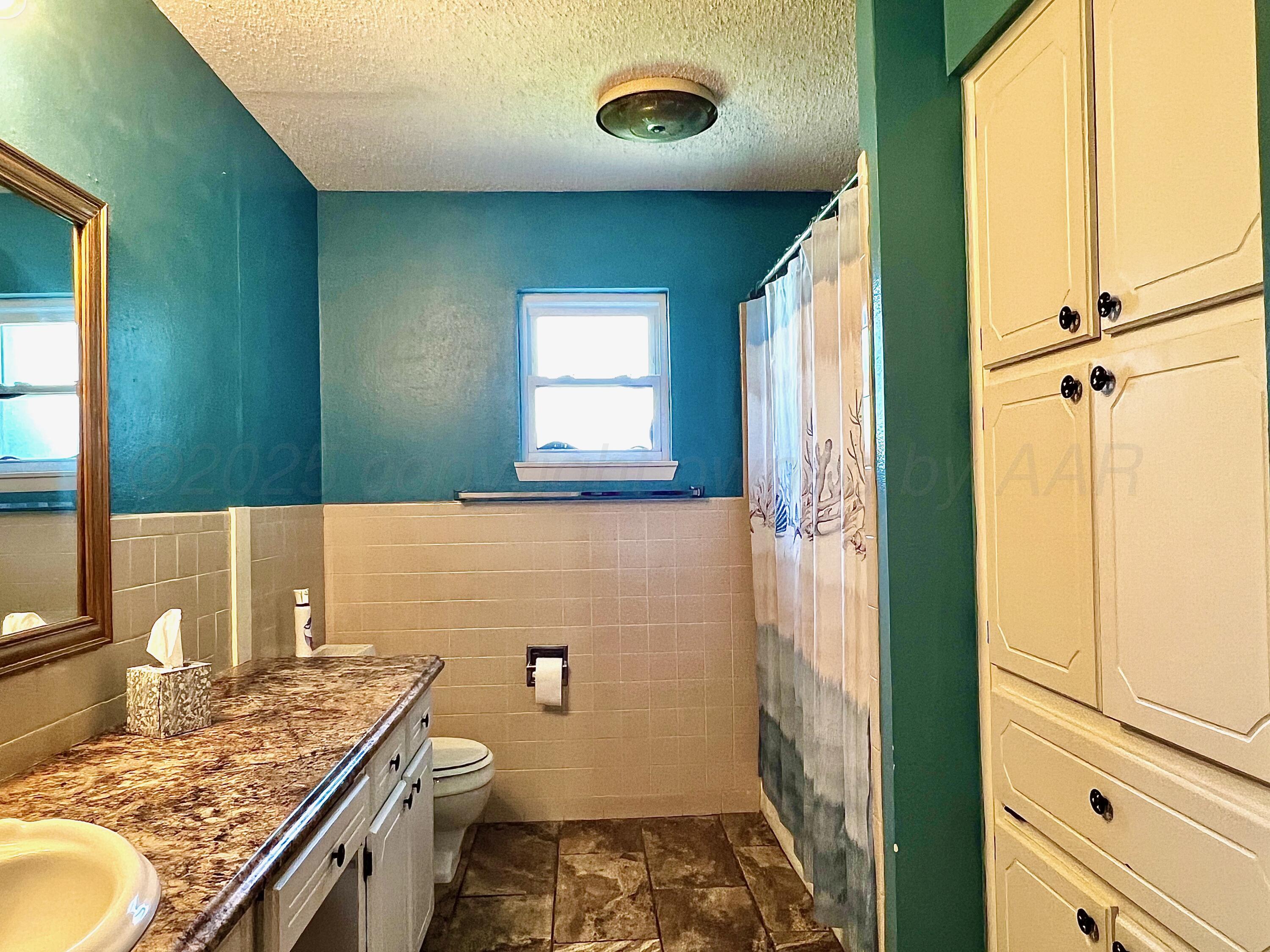 205 Houston Street Borger, TX 79007 - Photo 17 of 25 a bathroom with a granite countertop sink a toilet and a mirror