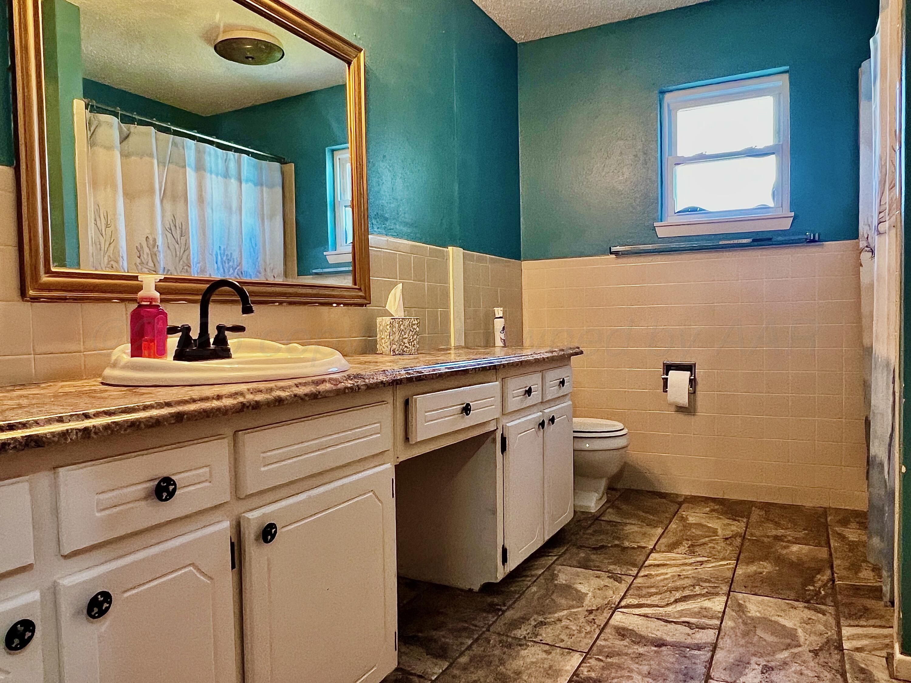 205 Houston Street Borger, TX 79007 - Photo 18 of 25 a bathroom with a granite countertop toilet sink and mirror