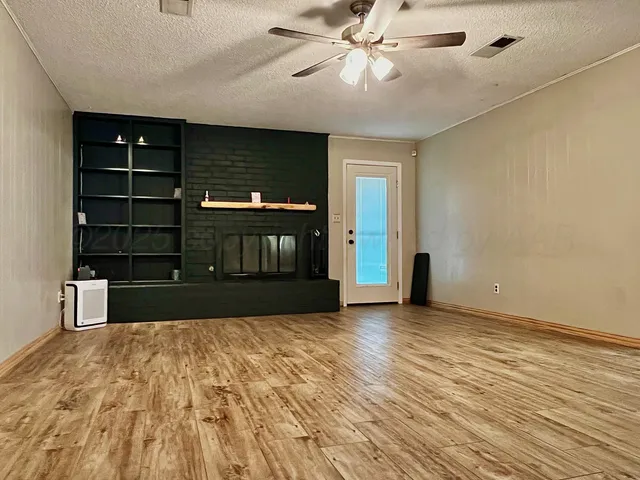 a view of an empty room with cabinet and a window