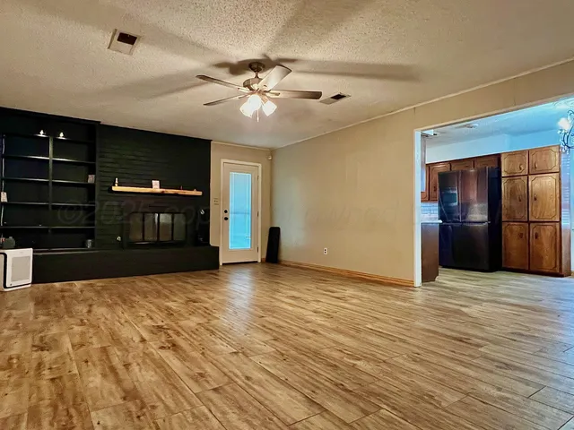 a view of an empty room with a fireplace and a chandelier fan