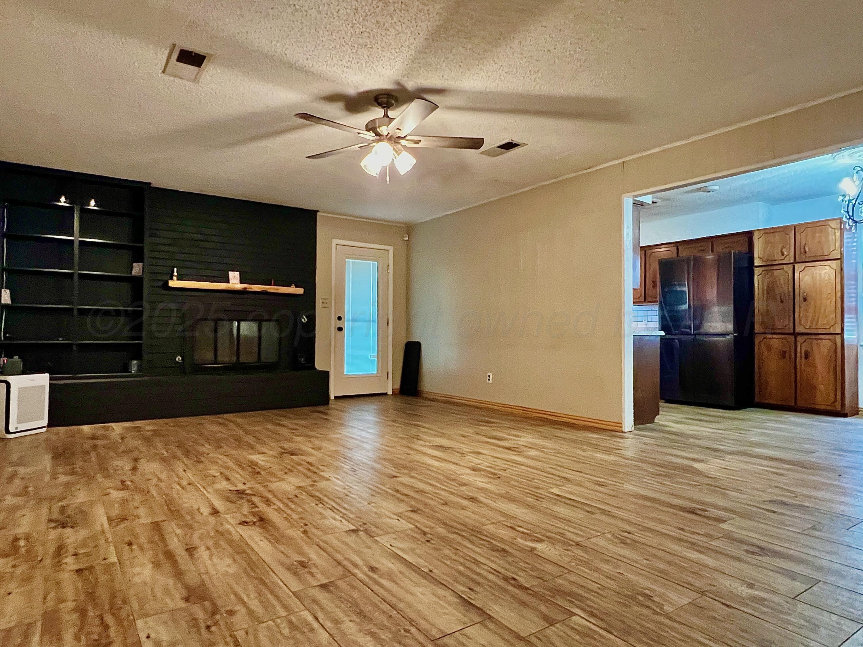205 Houston Street Borger, TX 79007 - Photo 8 of 25 a view of an empty room with a fireplace and a chandelier fan