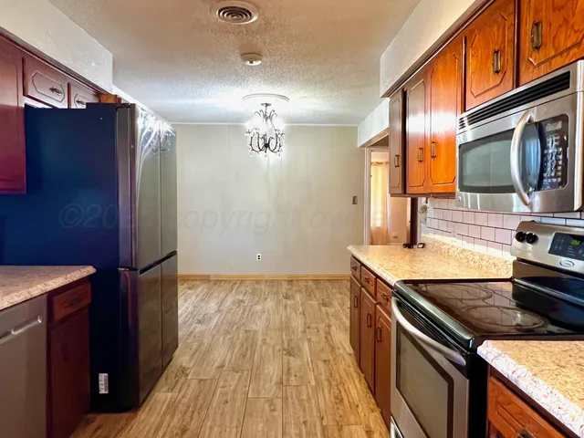 a kitchen with granite countertop a sink stove and refrigerator