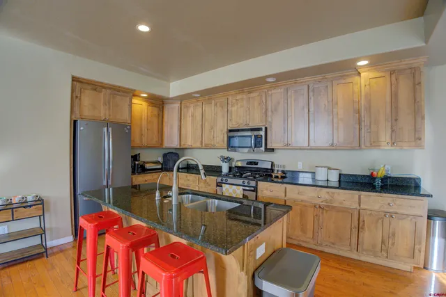 a kitchen with stainless steel appliances granite countertop a sink a stove and refrigerator