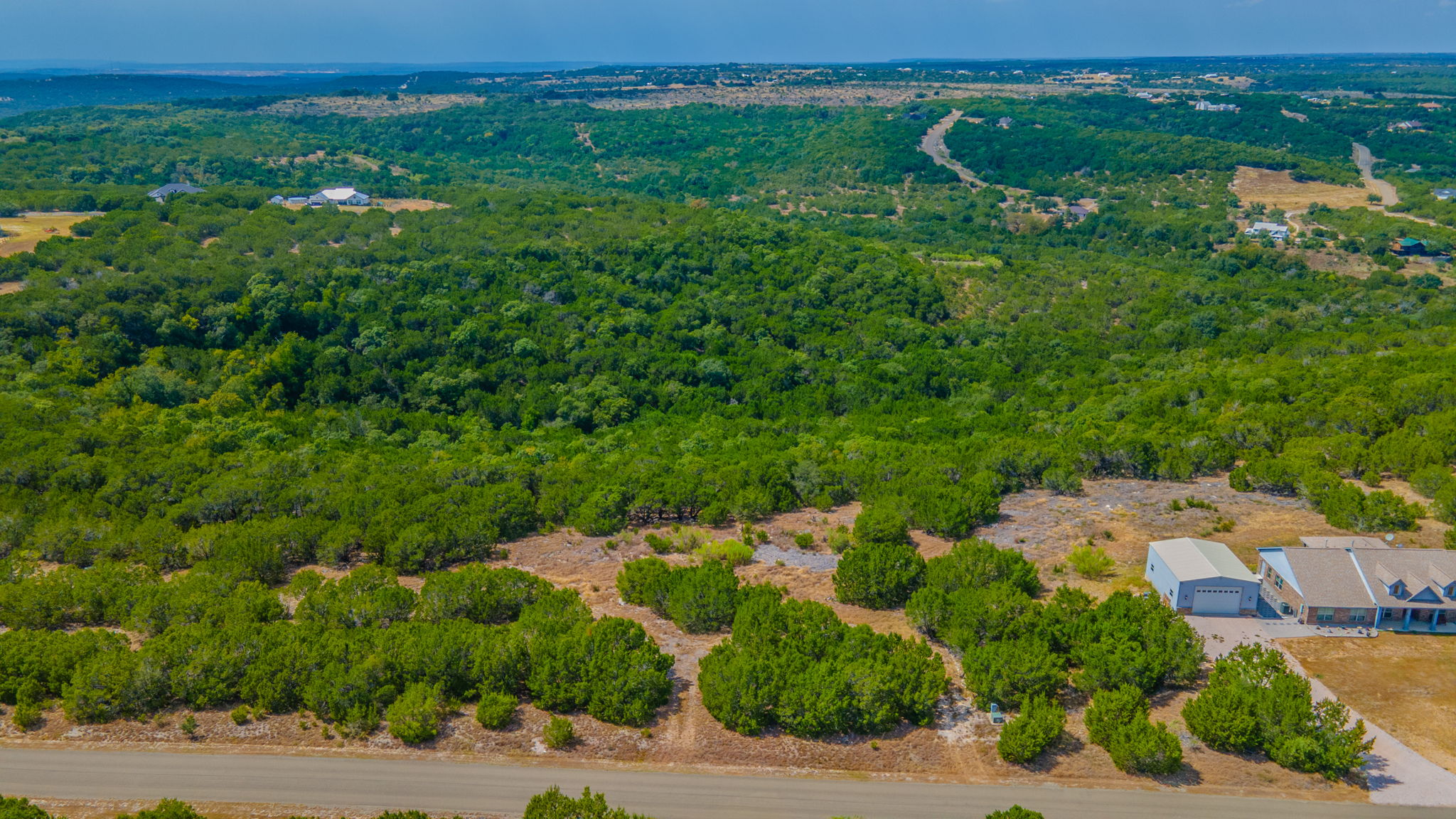 76 Balcones Ridge Way Bertram, TX 78605 - Photo 9 of 16 Rolling green hills stretch toward the horizon under a clear blue sky.
