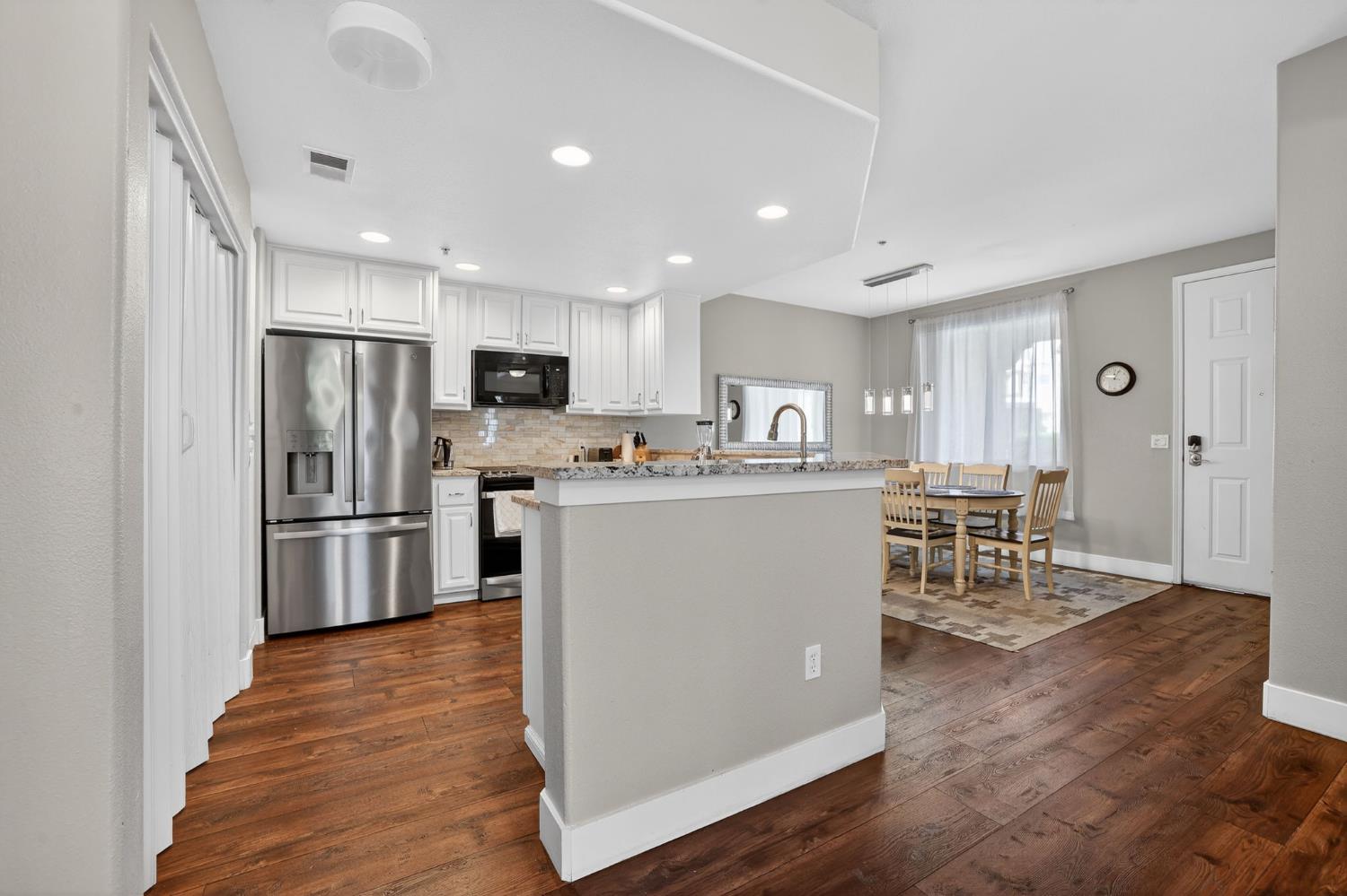 1501 Secret Ravine Parkway, Unit 1916 Roseville, CA 95661 - Photo 4 of 41 a kitchen with stainless steel appliances kitchen island granite countertop a refrigerator a stove a sink a dining table and chairs with wooden floor