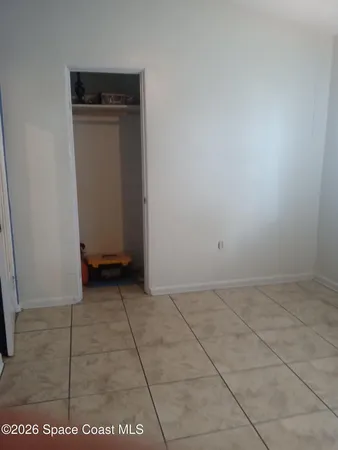 a view of an empty room with closet and a window