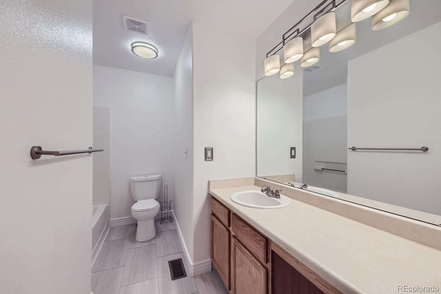 4512 Cornish Way Denver, CO 80239 - Photo 22 of 35 a bathroom with a sink a toilet a light fixture and a mirror