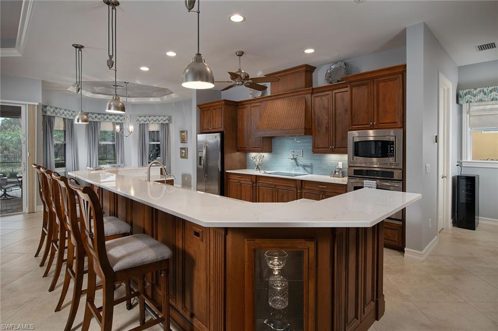 419 Saddlebrook Lane Naples, FL 34110 - Photo 6 of 24 a kitchen with kitchen island a dining table chairs stainless steel appliances and cabinets