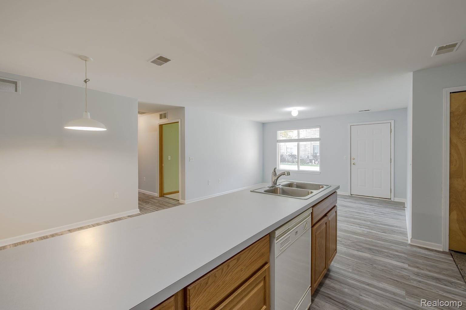 2154 Frazho Road Warren, MI 48091 - Photo 10 of 36 Kitchen island with dual basin sink, wood-finish cabinetry, and integrated dishwasher