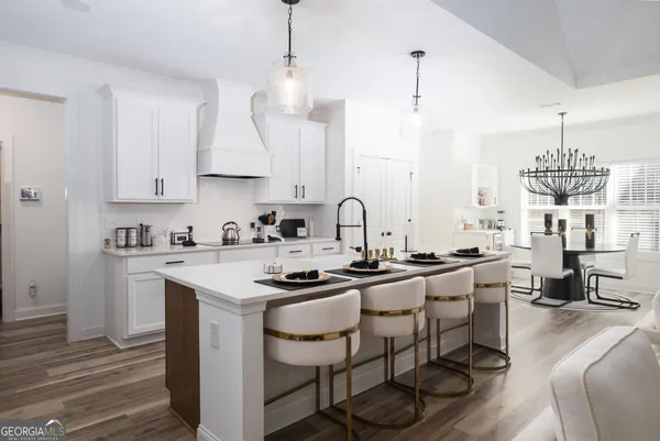 a kitchen with granite countertop a sink stove and white cabinets with wooden floor