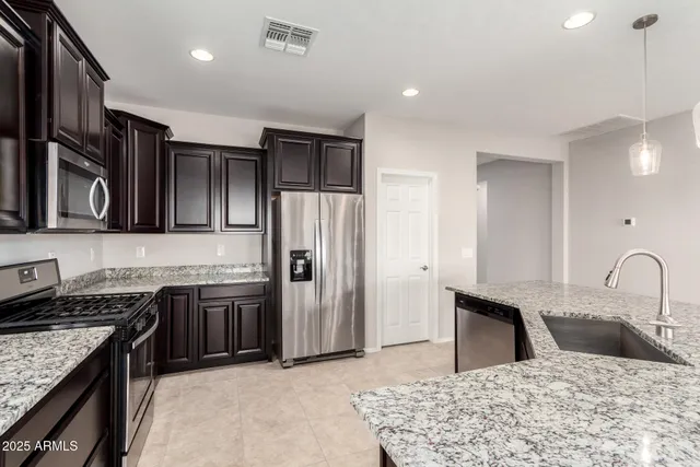 a large kitchen with granite countertop a large counter top a refrigerator and a sink