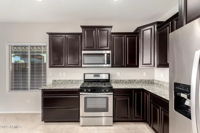 a kitchen with granite countertop kitchen island a sink stainless steel appliances and cabinets
