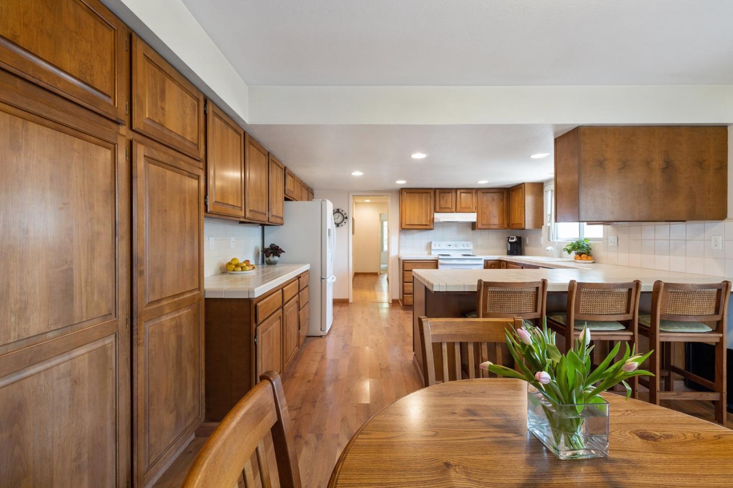1244 Surf Avenue Pacific Grove, CA 93950 - Photo 25 of 43 a kitchen with stainless steel appliances granite countertop a refrigerator a stove a sink a dining table and chairs with wooden floor