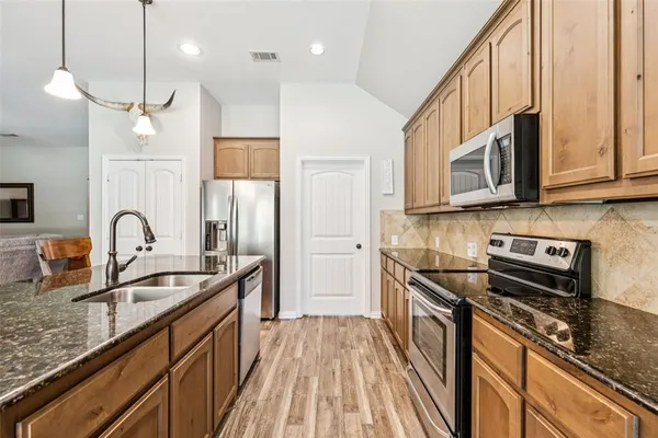 a kitchen with stainless steel appliances granite countertop a sink a stove and a refrigerator