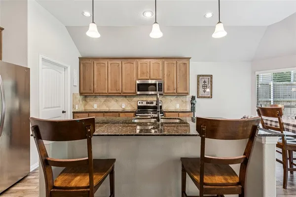 a kitchen with kitchen island a dining table chairs stainless steel appliances and cabinets