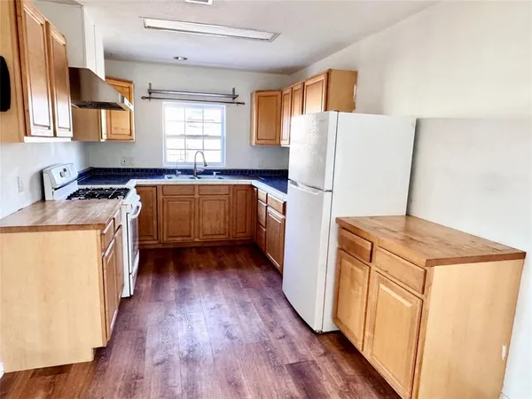 a kitchen with a refrigerator a sink dishwasher stove and wooden floor