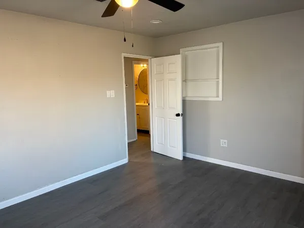an empty room with wooden floor and a ceiling fan