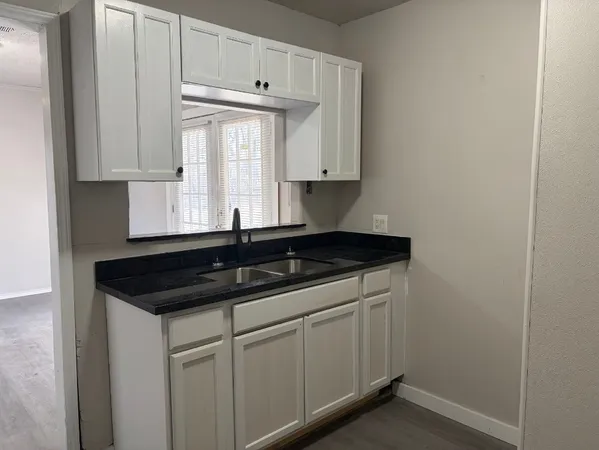 a kitchen with granite countertop white cabinets and a sink