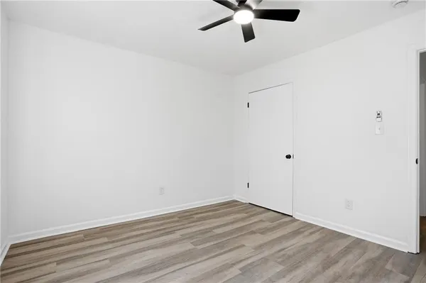 an empty room with a ceiling fan and wooden floor