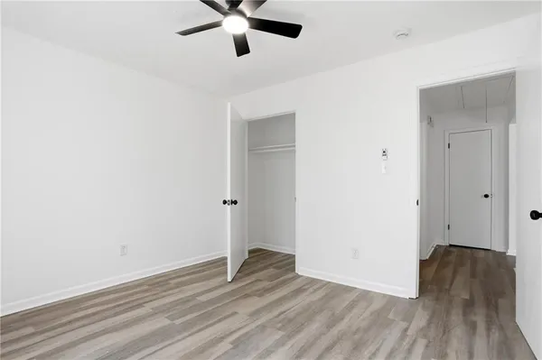 an empty room with wooden floor and a ceiling fan